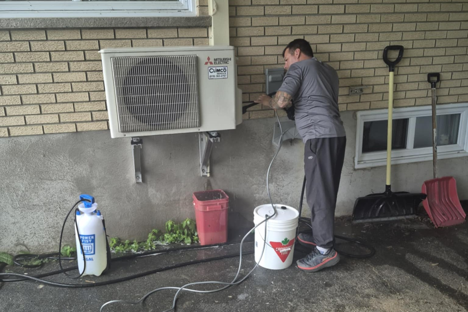 Technicien en ventilation nettoyant un climatiseur mural pour améliorer la qualité de l’air intérieur dans une résidence à Stanstead.